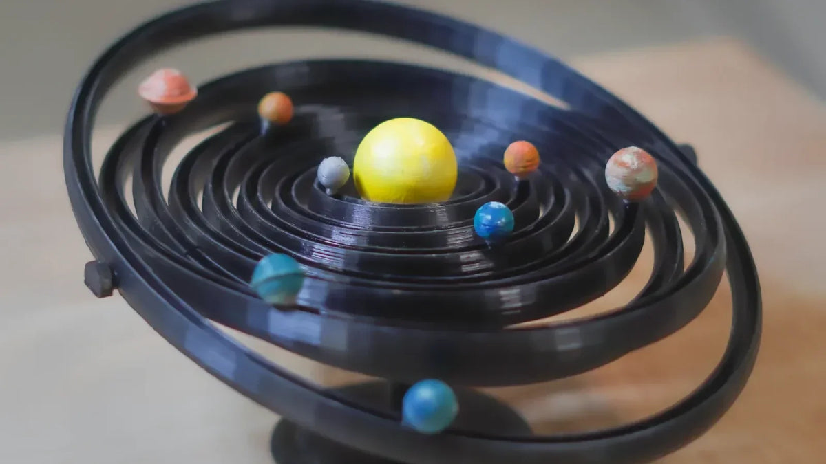 Sistema solar impreso en 3D con filamento PLA negro y planetas de colores, un proyecto de impresión 3D para el colegio