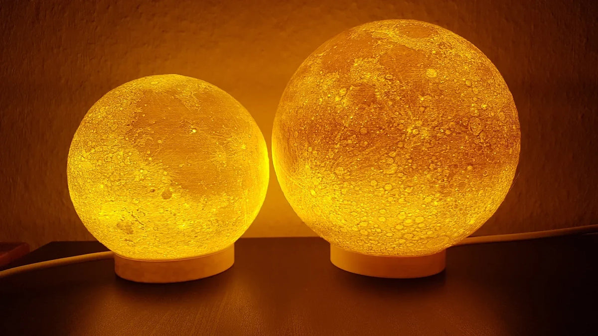 Dos lámparas de luna impresas en 3D encendidas con luz cálida, un regalo de Navidad impreso en 3D